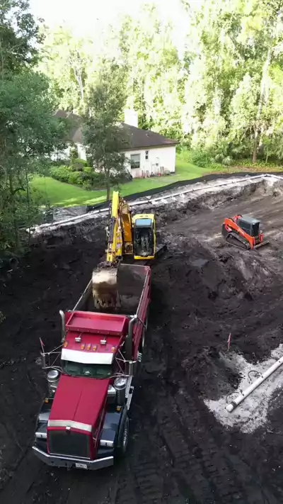 Aerial video of a Dirt Dynamics excavator loading a dump truck during dirt work on a Central Florida residential property
